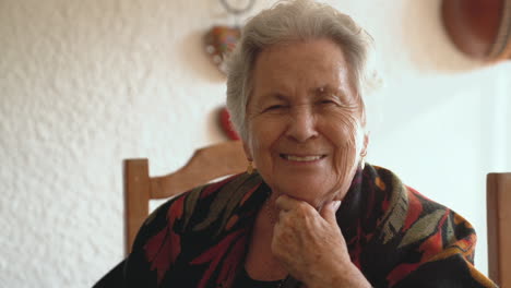 mujer mayor sonriente en un cálido chal en el comedor