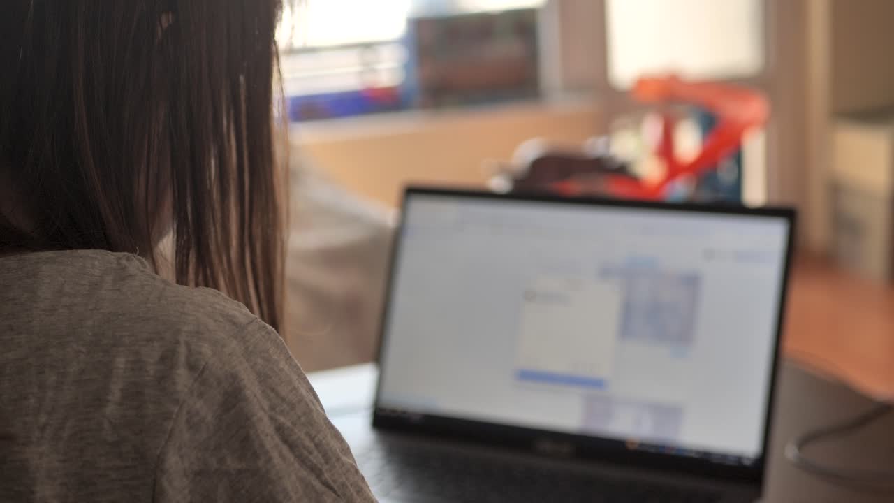 jovencita sentada en el sofá de casa, usando una laptop, viendo videos en línea, leyendo blogs, usando las redes sociales