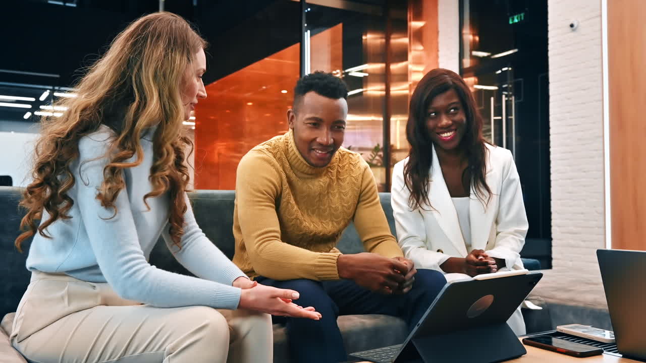 Multiracial group of workers in an office discussing business using a tablet. Slow motion