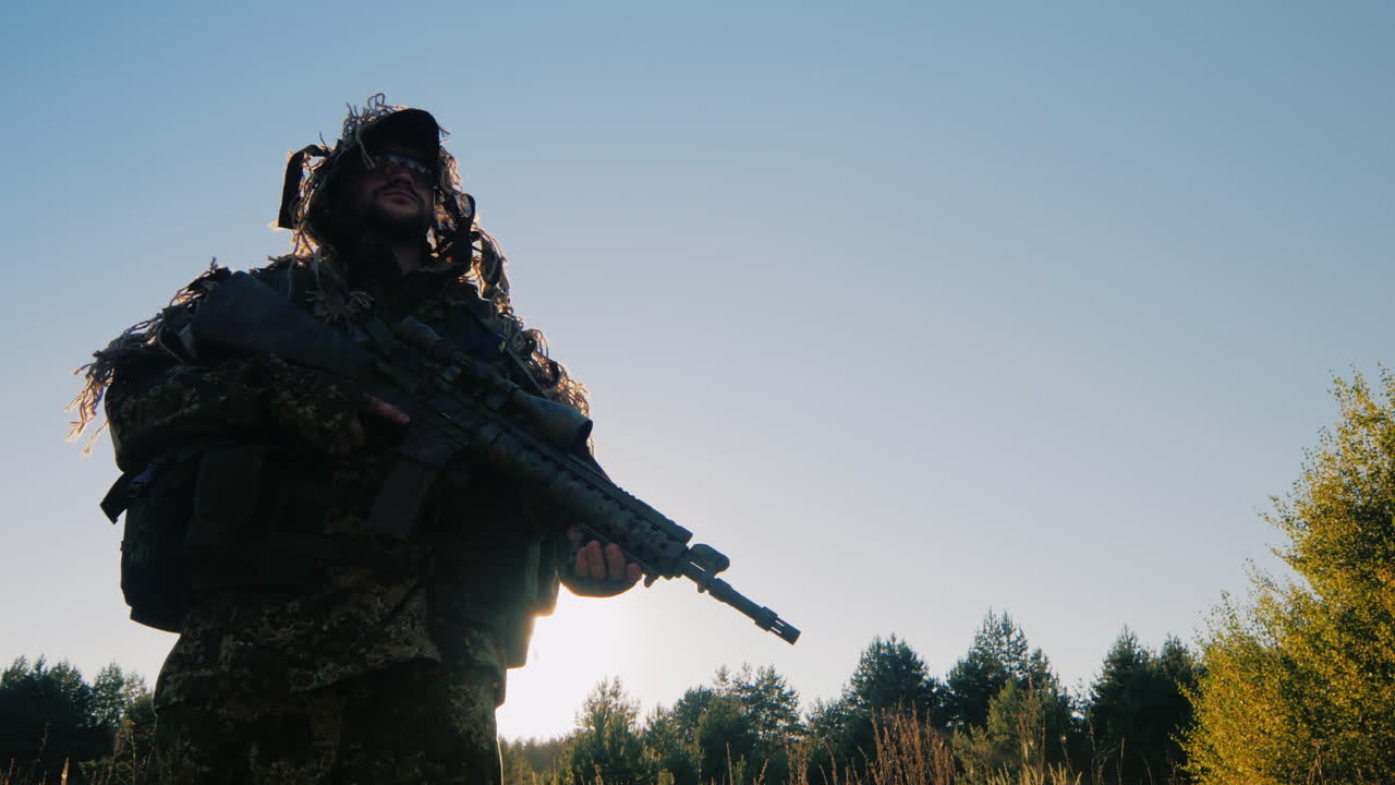 el soldado en la munición americana vale la pena contra el cielo el sol brilla en el ángulo inferior de sus brazos