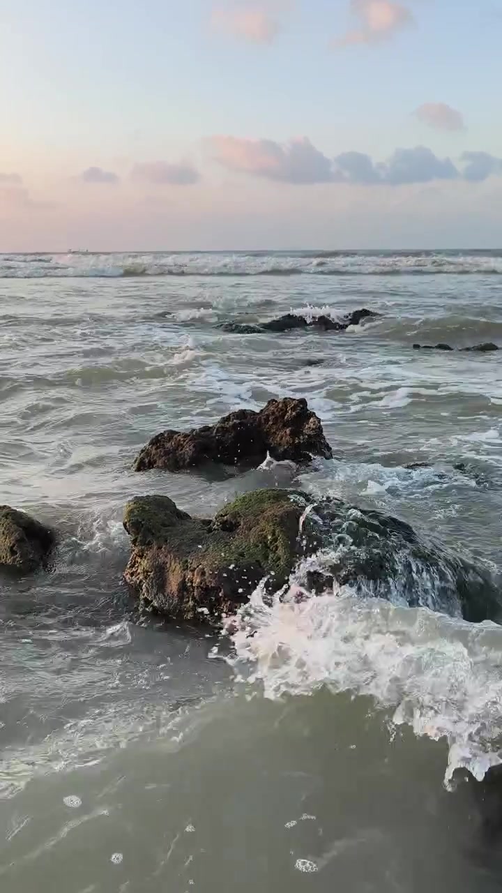 Onde dell'oceano che si infrangono dolcemente contro la costa rocciosa al tramonto