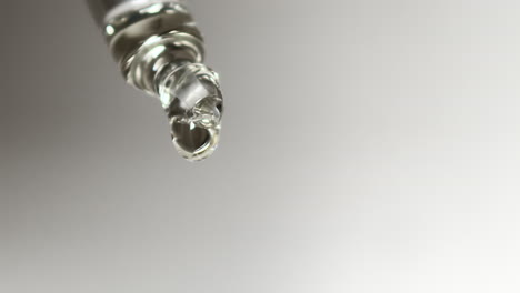 gota de agua se forma lentamente en el extremo de la pipeta de laboratorio de vidrio, macro, aislado