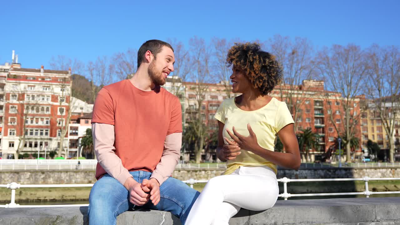 A couple conversing by the river in an urban setting