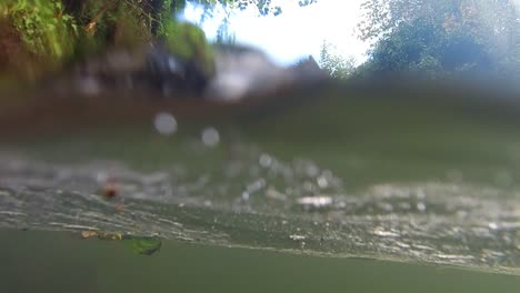 slow motion waterfall with camera dipping in and out of dirty water with debris floating