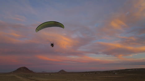 silueta de un parapente motorizado sobre el paisaje del desierto de mojave durante una puesta de sol épica