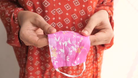 woman holding a pink floral face mask