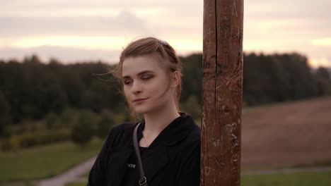 Portrait-of-a-young-woman-leaning-on-a-pole-in-the-wind