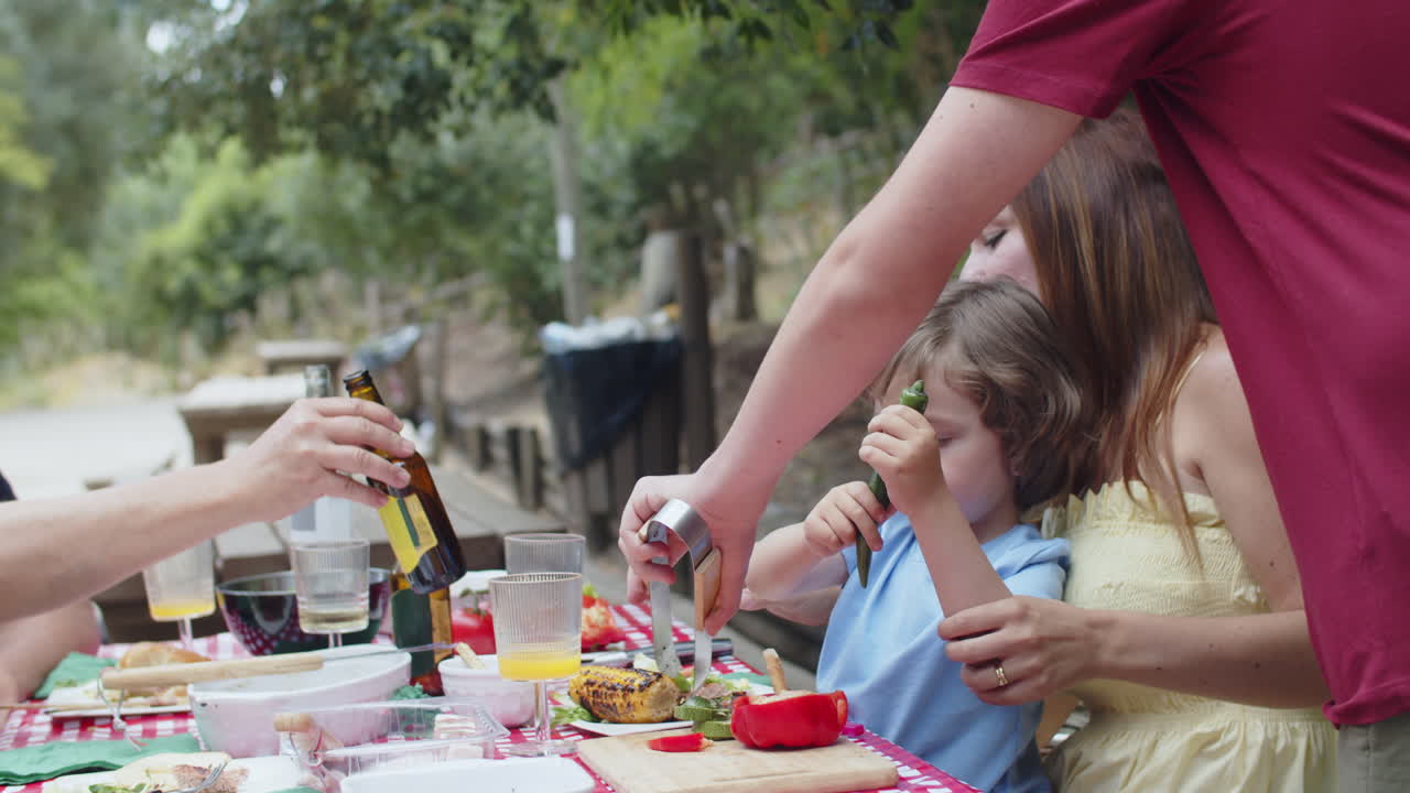 hijo caucásico poniendo comida de la parrilla en el plato de las madres