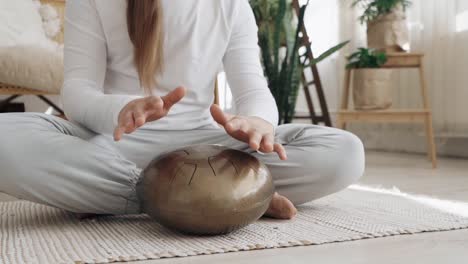 Mujer-Tocando-Un-Handpan-En-Su-Sala-De-Estar,-Música-Femenina-Usando-Un-Relajante-Instrumento-Musical-Zen