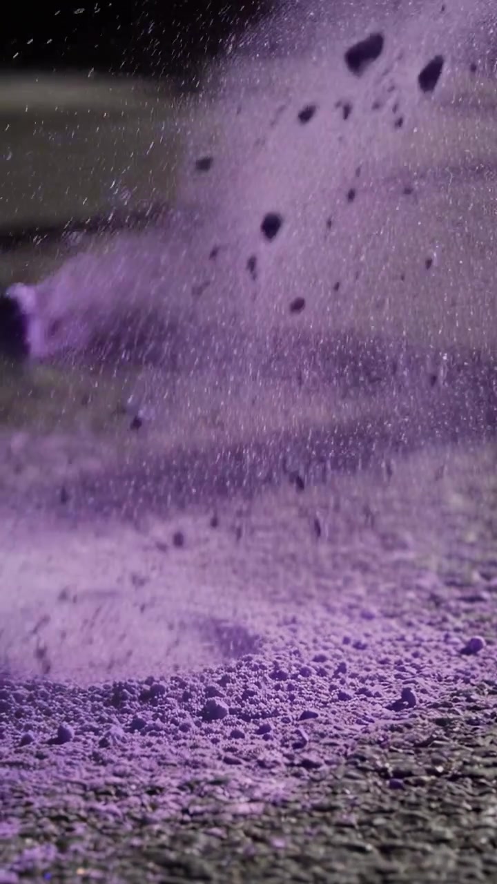Video verticale: Nuvola di pigmento viola che si espande, eruttando dopo un impatto fuori campo sul pavimento dello studio.