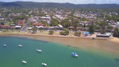 aerial revealing shot of beach view elite waterfront houses with turquoise water and parked boats in the suburb.