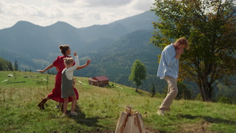 happy family funny dancing on mountain hill. parents playing game with children.