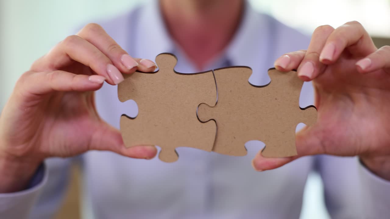 Hands Holding Two Connected Puzzle Pieces