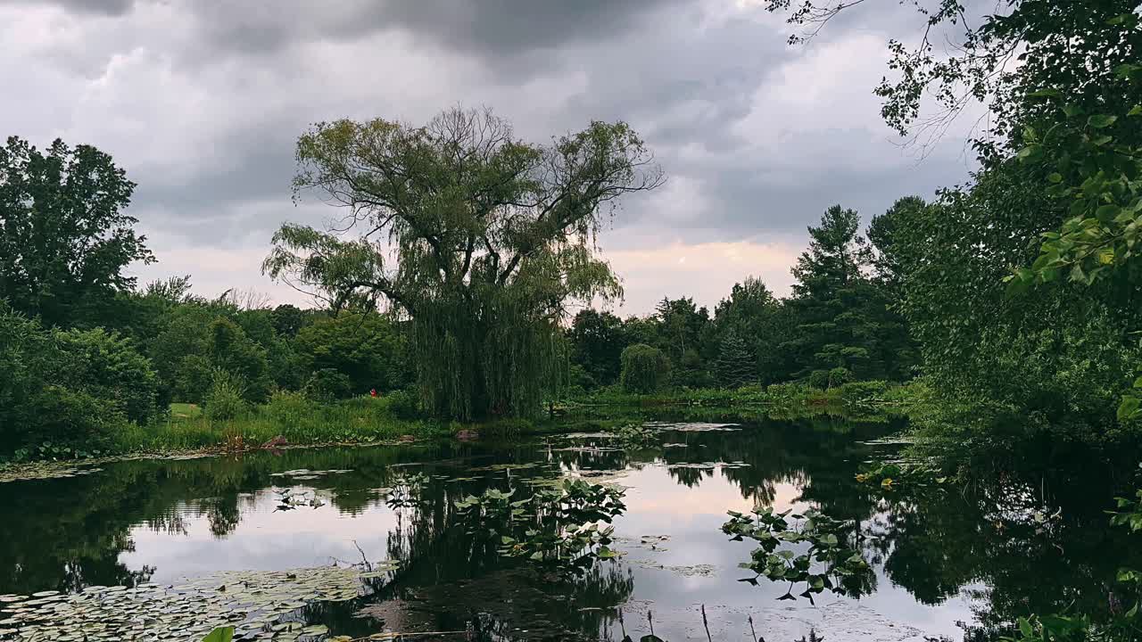구름이 가득한 하늘 아래 평화로운 연못 장면
