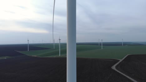 windmill farm on field, dolly in aerial view, passing wind turbine, wide shot
