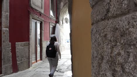 dolly left shot revealing woman walking down traditional covered narrow street, porto