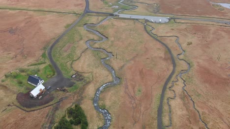 aerial video overlooking the lonely home outside waterfall bjarnarfoss and the parkinglot next to it with the paths and rivers moving around the landscape