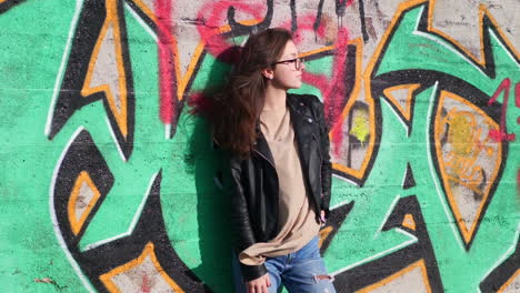 Teenage-Girl-in-Casual-Outfit-Posing-in-Front-of-Graffiti-Wall-on-Windy-Sunny-Day