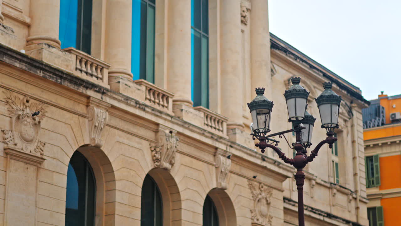 Close up of a street lamp with a blurred view of the Nice courthouse on the background