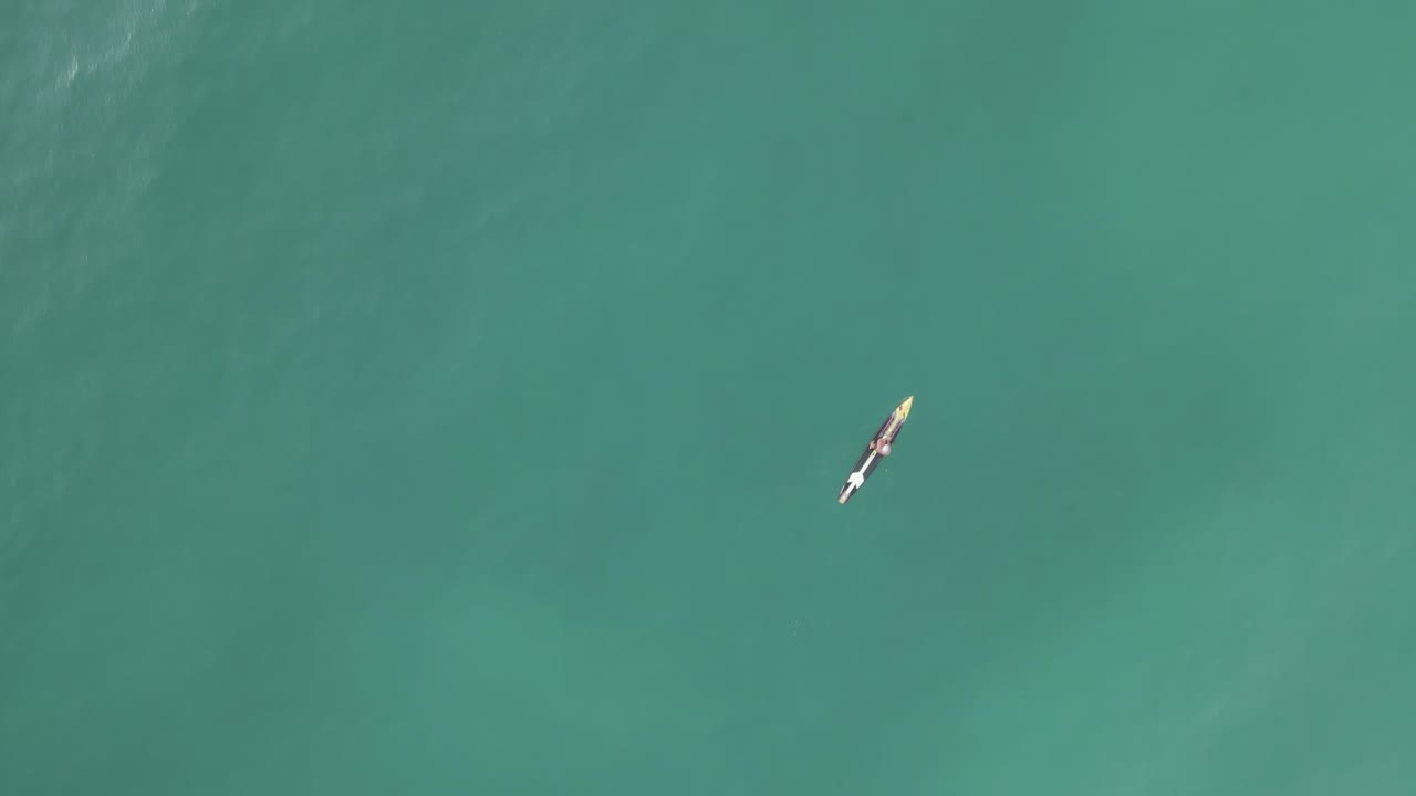vista aérea del hombre remando impresionante tabla larga en el océano verde jade