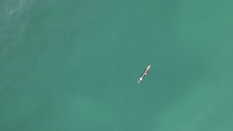 Overhead-view-of-man-paddling-stunning-long-board-in-jade-green-ocean