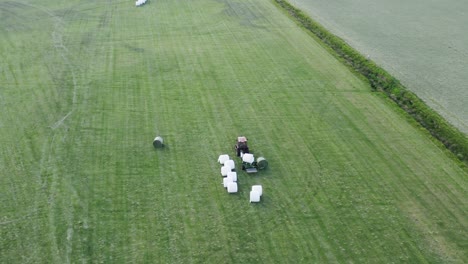 Balas-De-Heno-Girando-En-Una-Máquina-Envolviéndola-En-Papel-De-Aluminio-Blanco-En-Un-Campo-Verde-En-Islandia