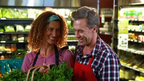 smiling staff checking leafy vegetables in organic section