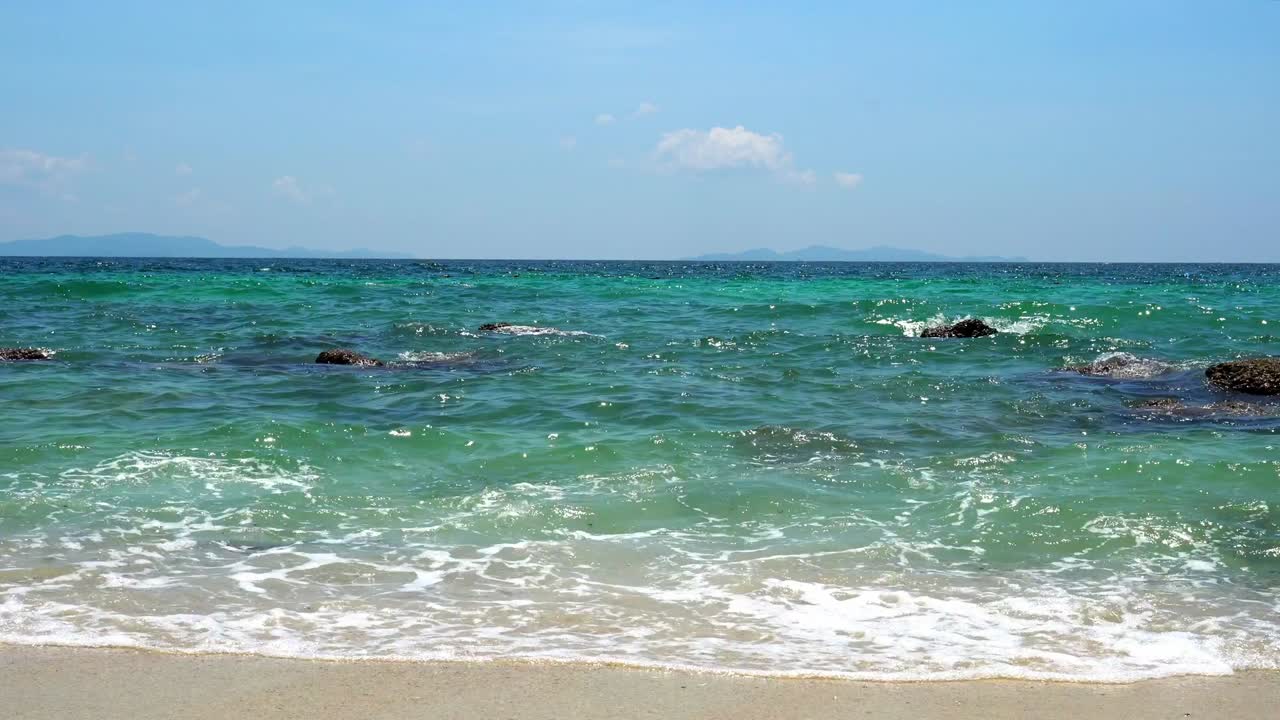 4km 풍경 선택적 초점 태양은 반이는 불꽃이 초록색 바다 표면과 바다 물 파도가 열대 모래 해변의 바위에 스프레이싱 하늘과 구름 배경
