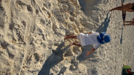 cámara lenta de un niño latino mexicano con una camiseta blanca y un sombrero azul corriendo por la arena en una playa de cancún, méxico