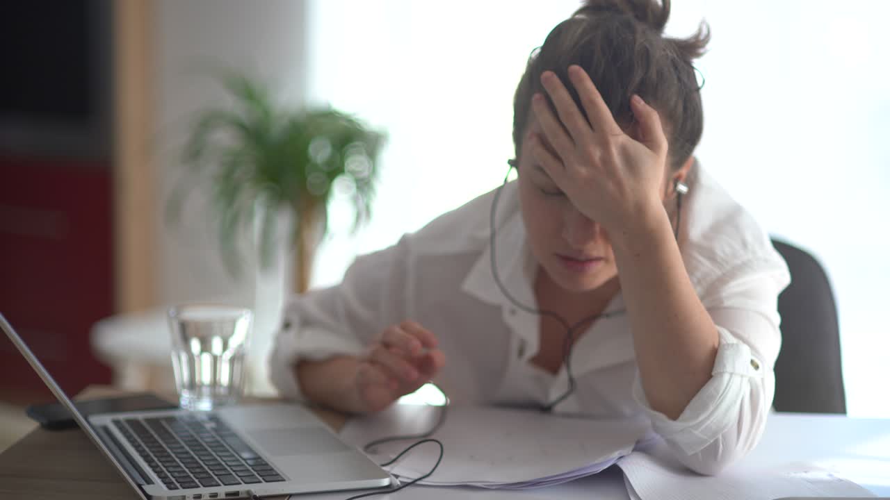 mujer molesta en una camisa blanca se sienta en una mesa en la oficina. reacción emocional, golpeando la cabeza en la mesa. crisis económica, fracaso empresarial