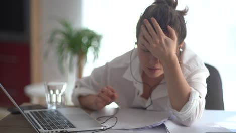 upset woman in a white shirt sits at a table in the office. emotional reaction, banging his head on the table. economic crisis, business failure