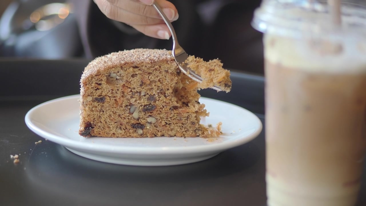 Person Eating a Slice of Carrot Cake in a Cafe