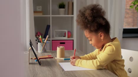 a happy little girl drawing and coloring with a blue pencil at her desk.a happy little girl drawing and coloring with a blue pencil at her desk