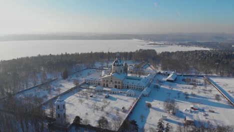 Aerial-view-of-the-Pazaislis-monastery-and-the-Church-of-the-Visitation-in-Kaunas,-Lithuania-at-winter,-snowy-landscape,-Italian-Baroque-architecture,-around,-dolly-zoom-in,-zooming-in