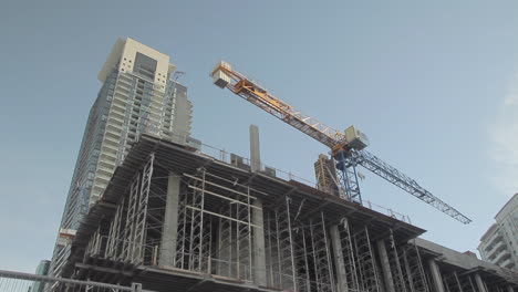 Far shot of crane on top of building in front of a tall building in downtown Toronto Canada
