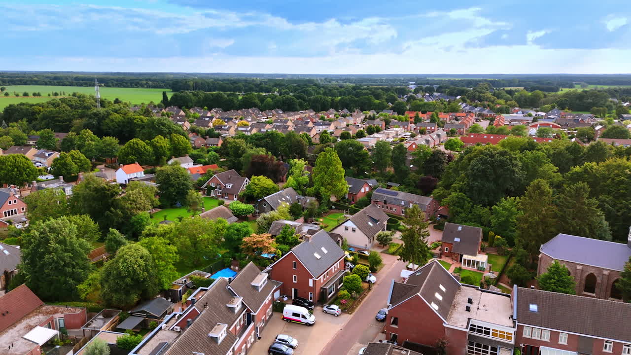 Aerial drone shot of Dutch neighborhood with houses and green trees. Drone shot of a Dutch neighborhood with houses, red rooftops, and many green trees in summer