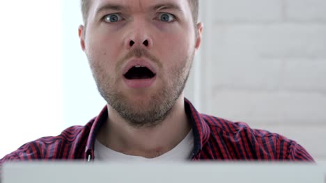 young man in shock while working on laptop