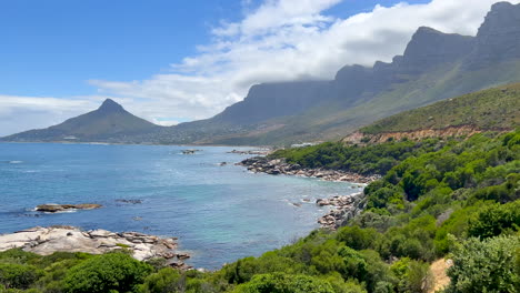 Oudekraal-Strand-Draufsicht-Kapstadt-Südafrika-Tafelberg-Felsbrocken-Ist-Seelöwenkopf-Atemberaubender-Ozean-Gebirgsküstenlinie-Aqua-Tiefblaues-Kristallklares-Wasser-Wolken-Rollen-über-Gipfel-Nach-Links