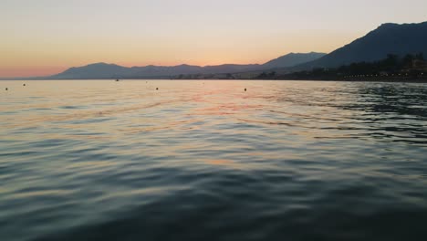 Drone-flying-over-the-calm-water-of-the-Mediterranean-sea-near-Marbella,-Spain