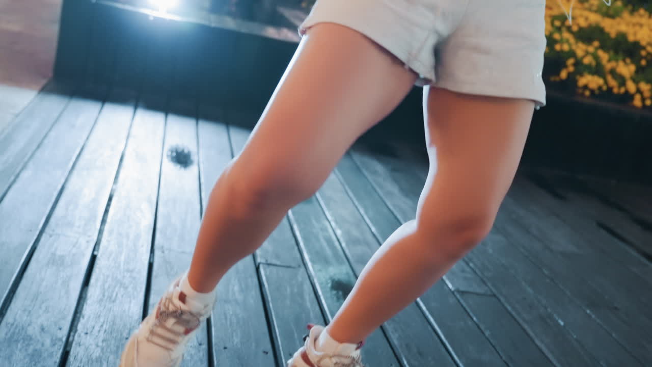 Ballerina sotto le stelle della città. Una giovane ballerina mostra passi vivaci sul tetto di un edificio di notte. Una giovane donna sicura di sé esibisce le sue abilità di danza freestyle su un tetto urbano illuminato dal bagliore della città.