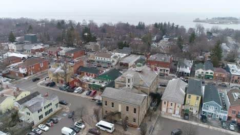 a drone captures an aerial view of niagara-on-the-lake's downtown courthouse, slowing zooming out on the surrounding historical buildings on a wintery day while snow lightly falls