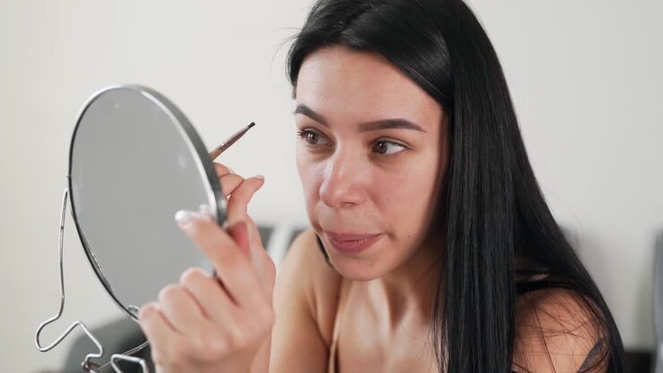 primo piano ritratto di una bella ragazza dai capelli neri dipinge le sopracciglia
