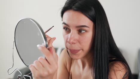 close-up portrait of a beautiful black-haired girl paints eyebrows