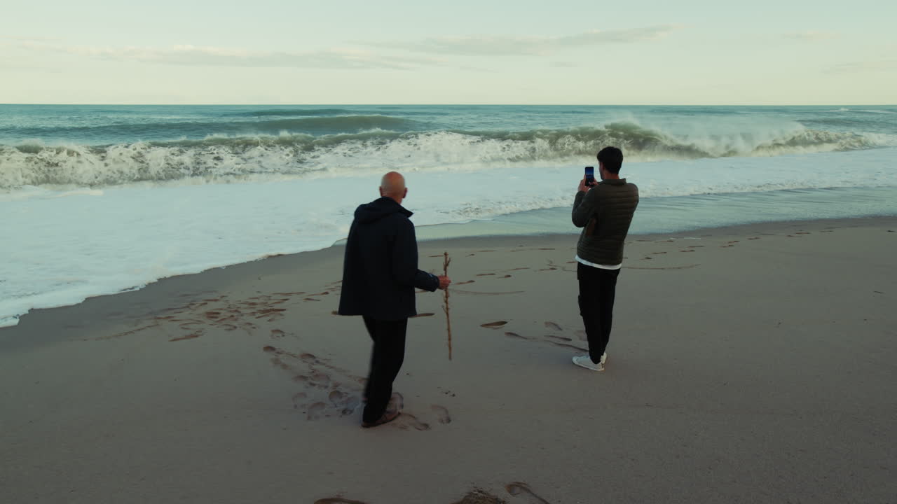 Father and Son Watch the Stormy Ocean Waves Crash on the Beach