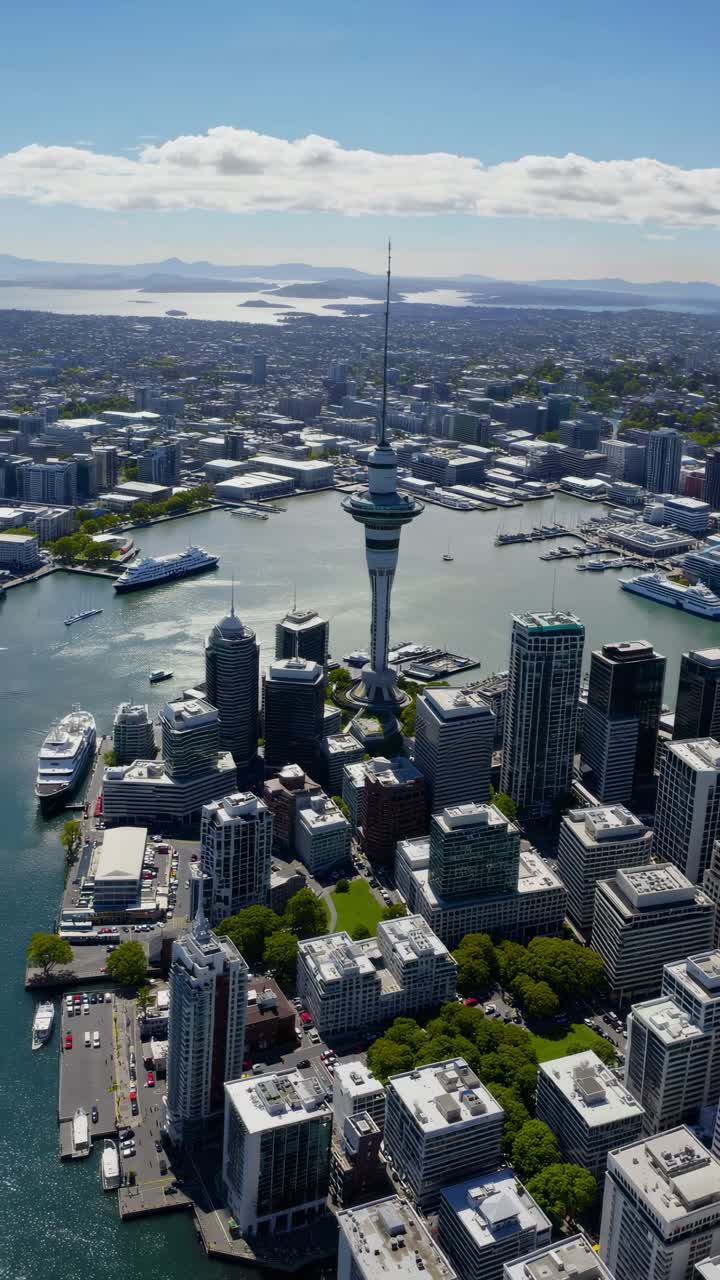 Aerial view video of a cityscape with skyscrapers and a prominent tower by the waterfront