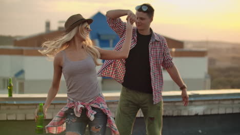 loving couple in plaid shirts dance on the roof. girl with beer spinning in dance with her boyfriend.