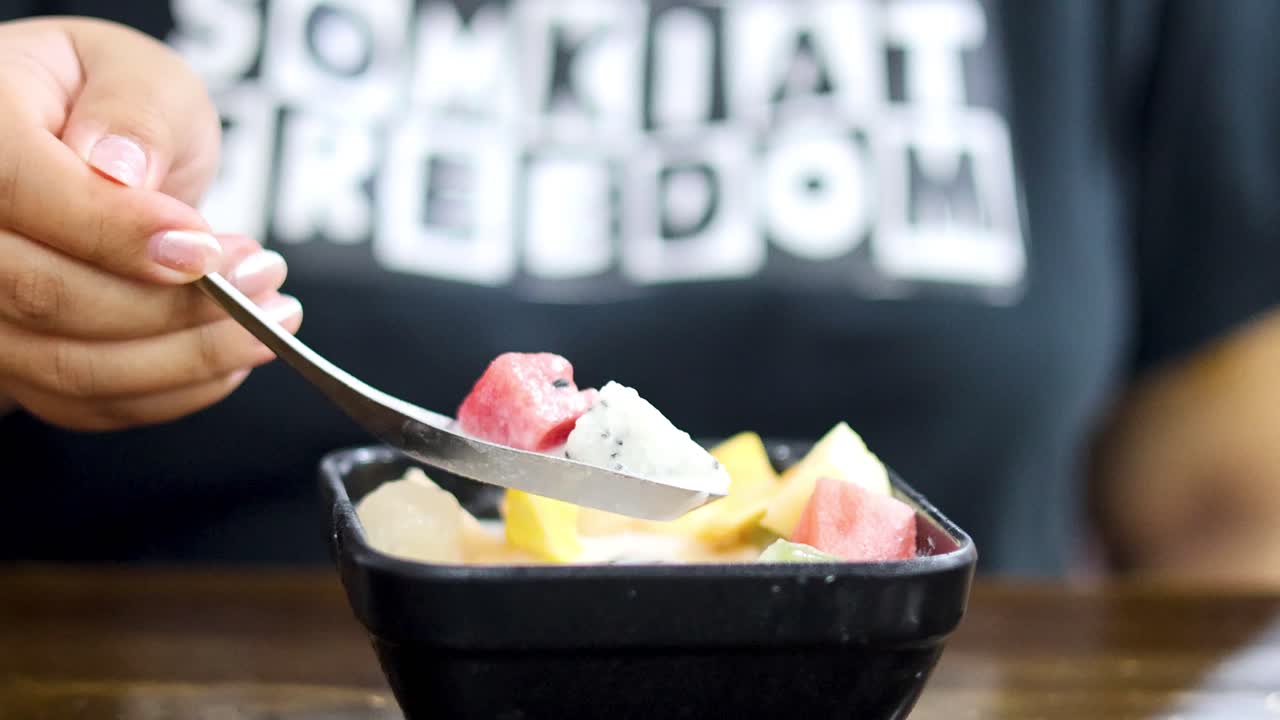 다채로운 과일 디저트를 먹는 사람