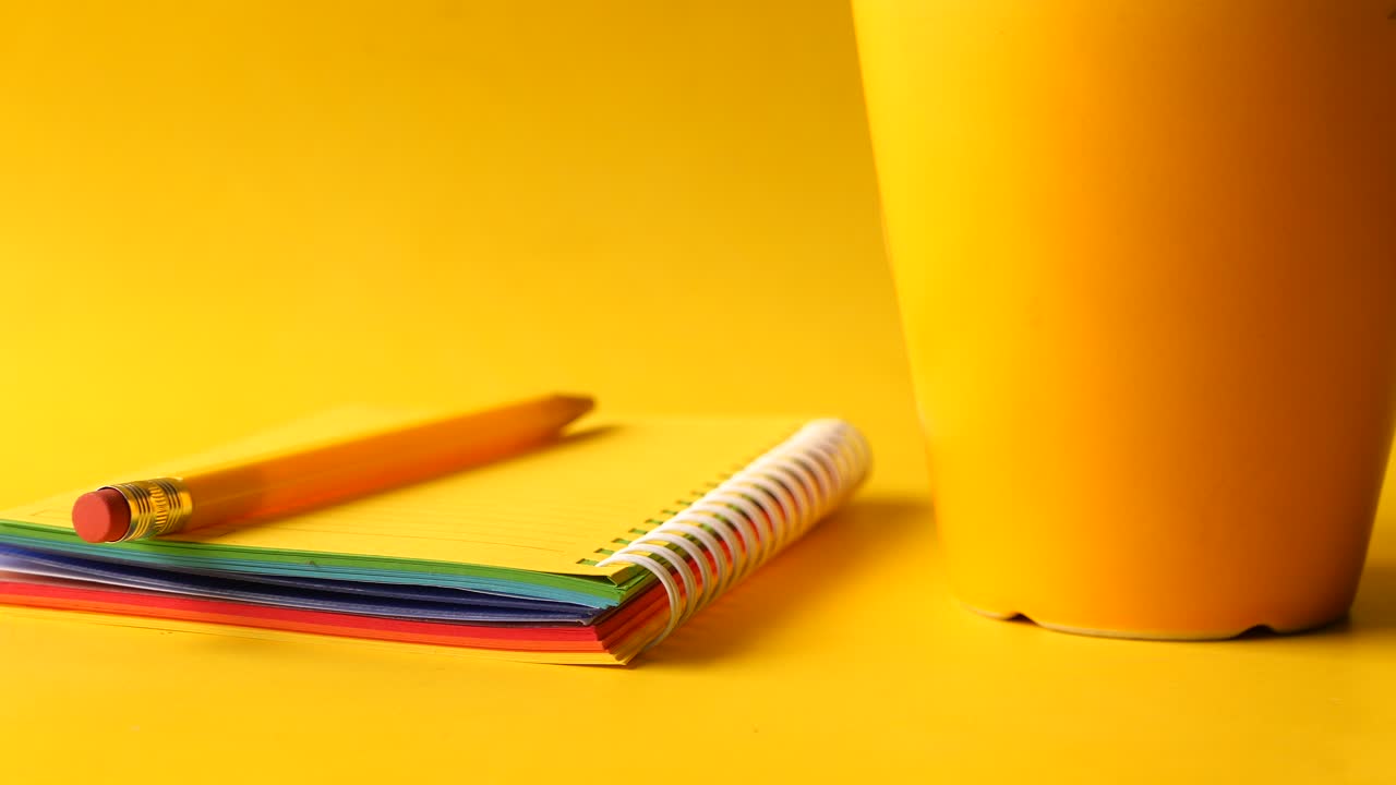 노란색 배경 에 있는 다채로운 노트북 과 노란색 컵