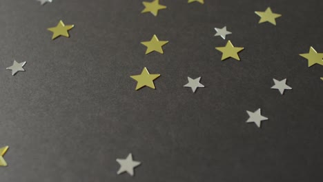 Video-of-multiple-gold-and-silver-stars-scattered-on-black-background