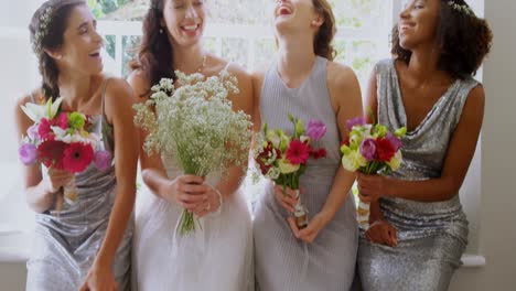 Bride-with-three-bridesmaids-laughing-and-holding-flower-bouquet-4K-4k